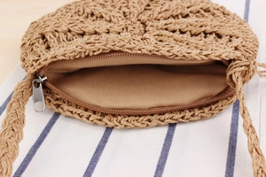 Detail showing the internal lining and zipper closure of the round woven paper straw bag