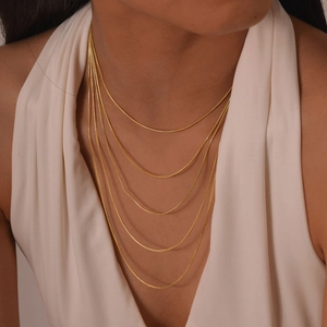 Détail d'un collier à 5 couches de chaînes serpent dorées porté par un mannequin