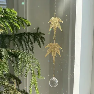 Golden maple leaf crystal suncatcher with prism ball reflecting rainbows in nature