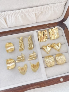 Close-up of assorted 14k gold plated irregular heart and square stud earring components