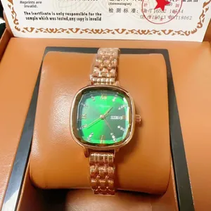 Detail of green square dial watch with gold strap showing calendar and weekday windows