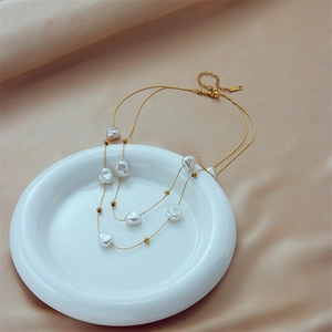 Baroque pearl double-layer gold titanium necklace displayed on a white ceramic plate