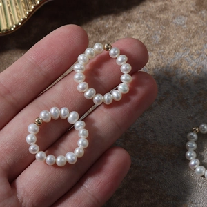 Elastic natural freshwater pearl ring with 14K gold filled bead on stone background