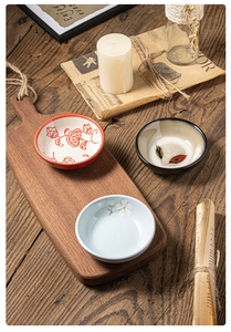 Tre ciotole per salse in ceramica con motivi floreali su un vassoio di legno vintage