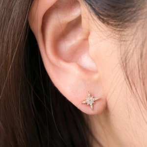 Detalle de un pendiente de estrella dorada con circonitas brillantes en la oreja