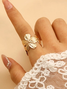 Detailed view of a gold flower ring with crinkle texture on a model with lace sleeve