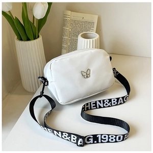 Detail of white nylon crossbody bag featuring silver butterfly decor and wide logo strap