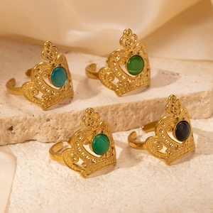 Set of four gold crown rings with colorful stones on textured stone and cream satin