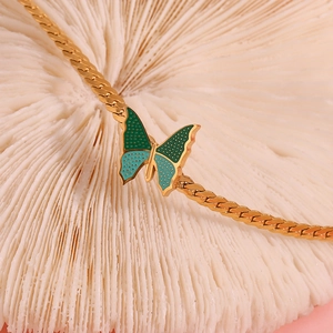 Macro shot of 18K gold-plated NK chain featuring a green and cyan butterfly pendant