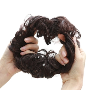 Deep brown curly synthetic hair bun extension with elastic band shown being stretched
