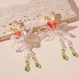Detail of floral earrings with resin flowers, glass bow, and emerald tassel droplets