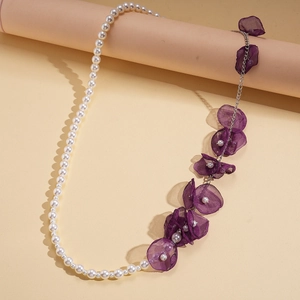 Elegant beaded necklace with white pearls and purple chiffon flowers on a display stand