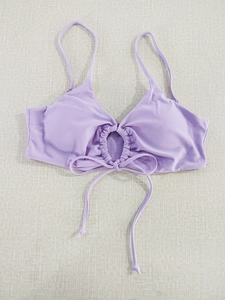 Detail of light purple bikini top with circular cutout, ruching, and adjustable bow tie