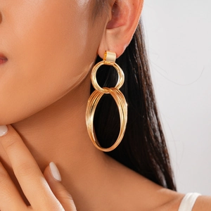 Close-up of gold layered concentric hoop earrings worn by a model in a minimal setting
