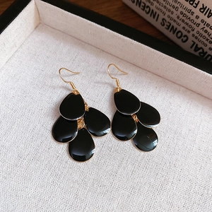 Detail shot of multi-layered black teardrop earrings on a cream textured display tray