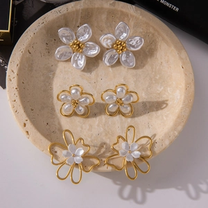 Detailed view of three pairs of 18K gold stainless steel flower earrings on a stone tray
