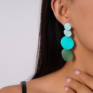 Detail view of long geometric gradient teal earrings worn by a model in profile