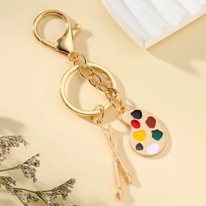 Artistic gold palette and paintbrushes keychain with vibrant enamel dots for car keys