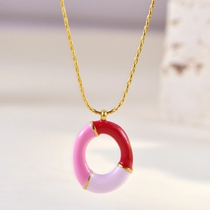 Close-up of pink and purple enamel round pendant on a gold chain necklace