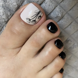 Detail of white toenails with black tulip patterns and solid black finish on plush fabric