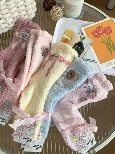 Close-up of cozy coral fleece socks with cute animal embroidery and satin ribbon detail