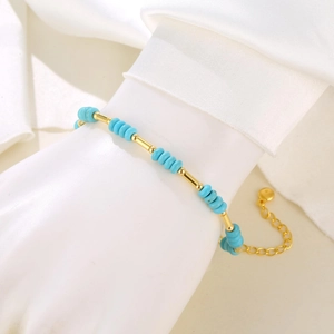 Detail of adjustable beaded bracelet with blue discs and golden metal accents on wrist