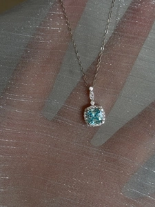 Detail of silver necklace with square light blue gemstone pendant and micro-pave crystals