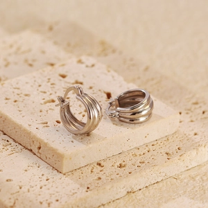 Macro view of silver S925 layered hoop earrings on textured travertine stone