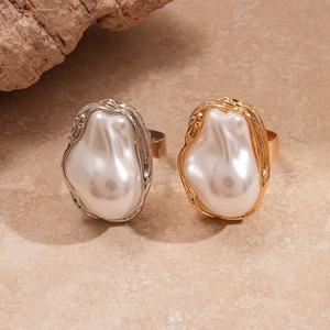 Close-up of gold and silver baroque rings featuring irregular pearls and wrinkled texture