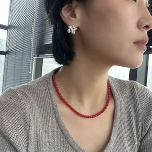 Minimalist red bead necklace with silver flower stud earrings worn by Asian model