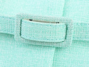 Détail macro du tissu en tweed vert menthe et boucle de ceinture rectangulaire assortie