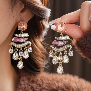 Macro detail of vintage gold earrings with pink gemstones and crystals on model