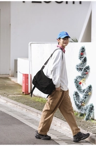 Outdoor shot of a black canvas messenger bag worn with khaki pants and a white shirt