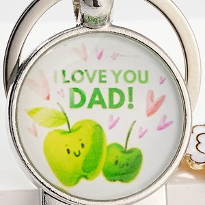 Close-up of a silver beer keychain featuring green apples and I Love You Dad text