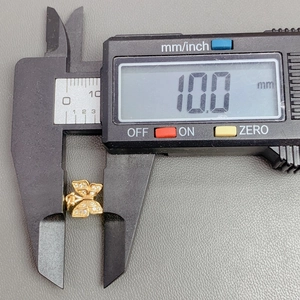 Detailed measurement of a gold crystal butterfly pendant showing 10.0mm width on a caliper