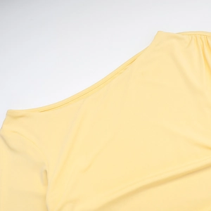 Detail view of yellow knit fabric showing the asymmetric shoulder seam and texture