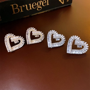 Elegant gold and silver heart stud earrings with sparkling zircons on a vintage book