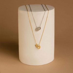 Detail view of gold and silver interlocking ring necklaces with white opal stone inlay
