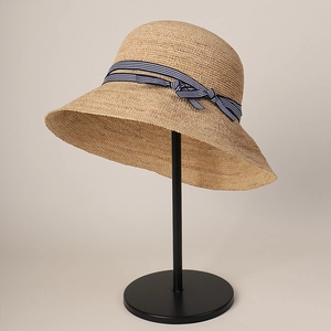Close-up of woven straw sun hat with blue and white striped ribbon and elegant bow