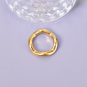 Polished wavy gold stainless steel ring with irregular curved design on purple backdrop