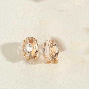 Dettaglio di orecchini di cristallo ovale con castone a quattro griffe in oro 14K