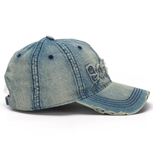Detail of washed blue denim baseball cap with vintage distressed holes and 3D embroidery
