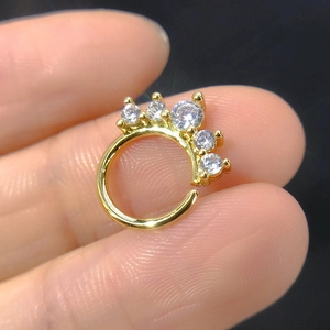 Close-up of a gold nose ring with five graduated cubic zirconia stones held by fingers