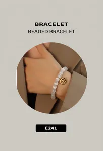 Detail of beaded bracelet with white opal stones and gold Fu character charm on wrist