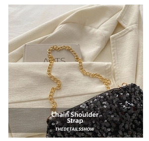 Close-up of black sequin flap bag with gold chain strap on textured white blazer
