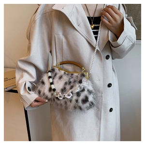 Détail du sac à main en peluche avec bandoulière perle et poignée en bois sur modèle