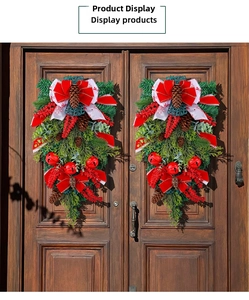 Close-up of Christmas teardrop swags with red bells and pine cones on wooden doors