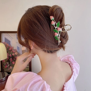 Detail of a pink strawberry hair claw clip with pearls worn in a bun hairstyle