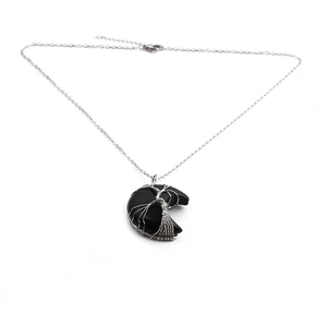 Macro detail of black crescent moon pendant with silver wire wrapped tree of life design