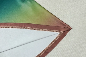 Close-up of a gradient dress hem featuring meticulous brown piping and overlock stitching